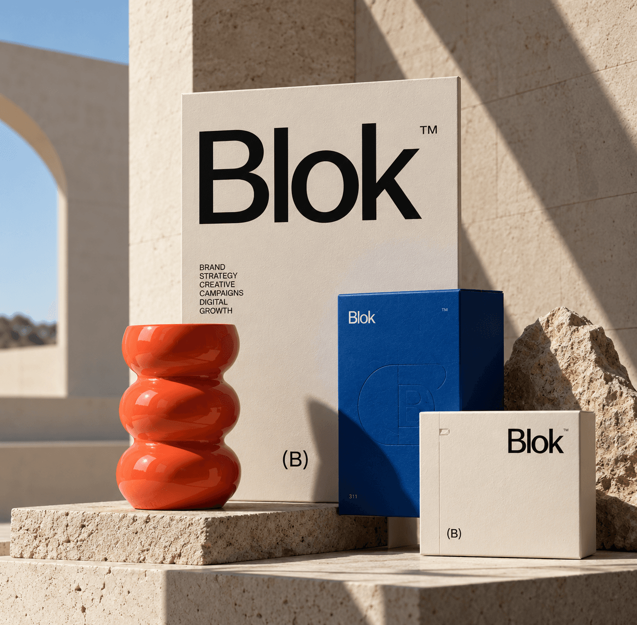 Brand packaging boxes and a glossy orange vase arranged on sunlit stone steps